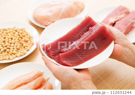 タンパク質の多い食材を持つミドル女性（カツオ） 112031244