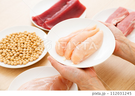 タンパク質の多い食材を持つミドル女性（鶏のささみ） 112031245