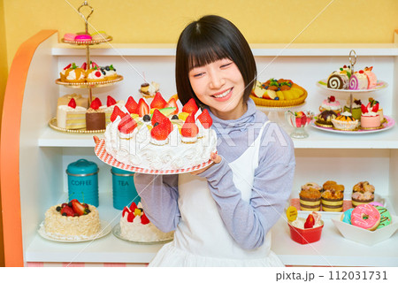 ホールケーキを手にする若い女性 112031731