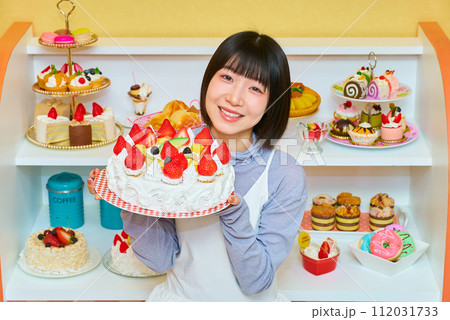 ホールケーキを手にする若い女性 112031733