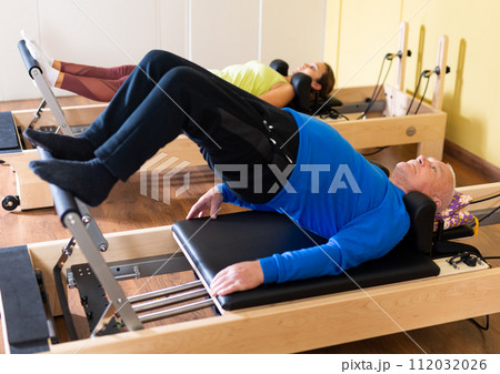 Senior man doing stretching exercises on pilates reformer 112032026