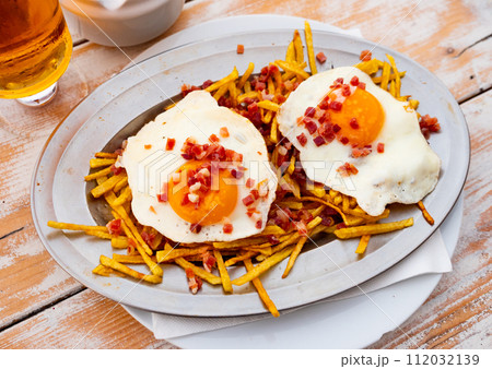 Fried eggs with french fries sprinkled with cured ham Fried eggs with french fries sprinkled with cured ham 112032139