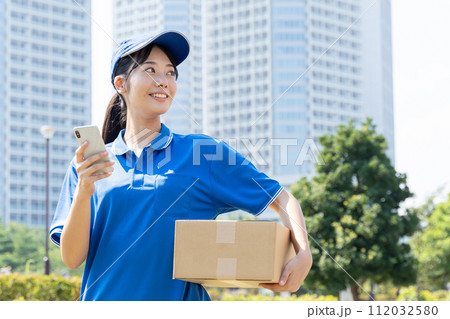 荷物を運ぶ宅配便の若い女性スタッフ 112032580