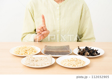 食物繊維を多く含む食品と人差し指を立てるミドル女性 食物繊維を多く含む食品と人差し指を立てるミドル女性 112032905