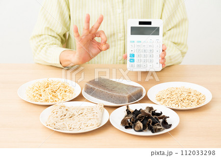 食物繊維を多く含む食品と電卓を持って丸サインをするミドル女性 食物繊維を多く含む食品と電卓を持って丸サインをするミドル女性 112033298
