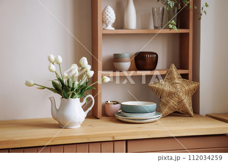 Stylish interior of a wooden Scandinavian kitchen. Fresh flowers in a vase. Stylish interior of a wooden Scandinavian kitchen. Fresh flowers in a vase. 112034259