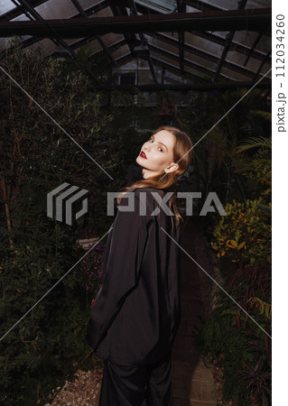 Female model illuminated by a light source against a background of foliage 112034260