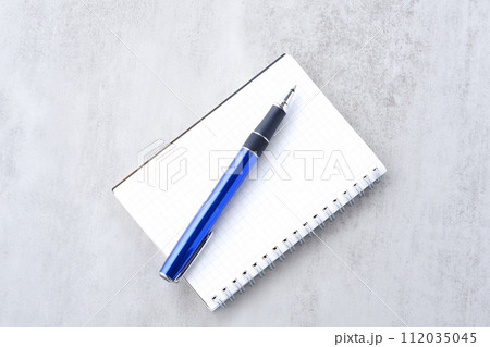 リング式のメモ帳とペンでデスクワークをしているイメージ 112035045