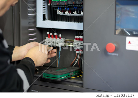 electrician connecting wires in control cabinet 112035117