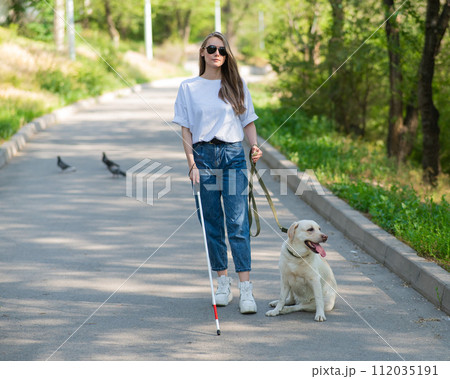 Blind woman walking with guide dog in the park. Blind woman walking with guide dog in the park. 112035191