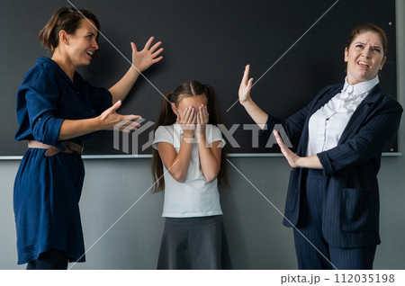 Schoolgirl and her mother yell at the teacher standing at the blackboard. Schoolgirl and her mother yell at the teacher standing at the blackboard. 112035198