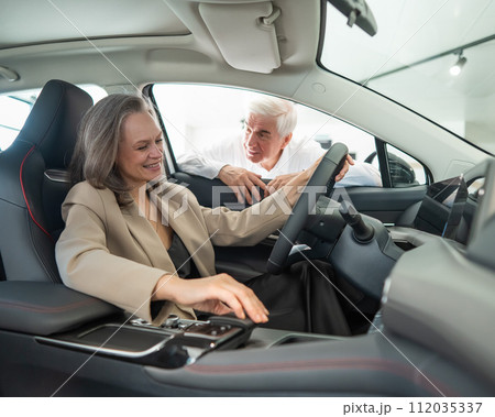 An elderly couple chooses a new car at a car dealership. Mature woman driving.  112035337
