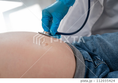 The doctor listens to the heartbeat of the baby of a pregnant woman. The doctor listens to the heartbeat of the baby of a pregnant woman. 112035424