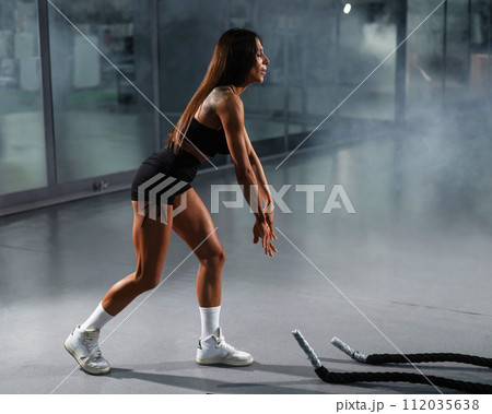 Caucasian woman doing exercise with ropes. Caucasian woman doing exercise with ropes. 112035638