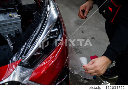 The process of applying protective vinyl film to car headlights in detailing.  112035722