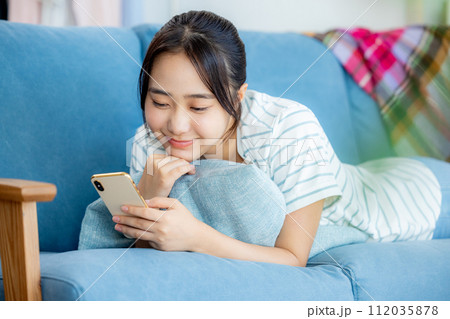 リビングでスマホを見る若い女性 リビングでスマホを見る若い女性 112035878