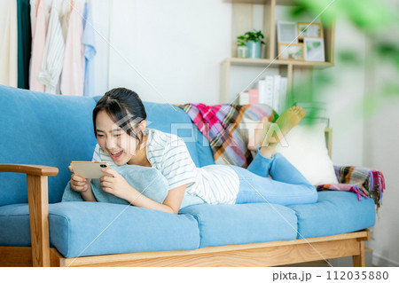 リビングでスマホを見る若い女性 112035880