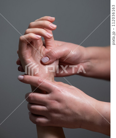 The masseuse massages the client's palms. Close-up of hands at a spa treatment. Vertical photo.  112036163