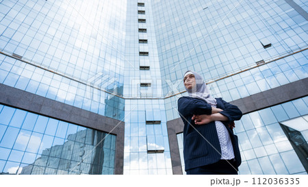 Portrait of a pregnant business woman in a hijab and a suit with crossed arms on her chest outdoors. 112036335
