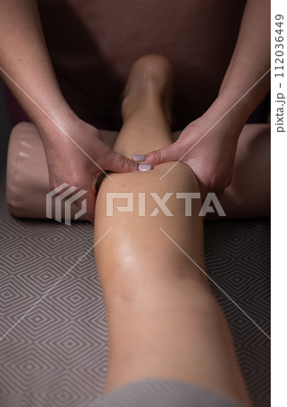 Close-up of a woman's leg massage in a salon. Vertical photo. 112036449
