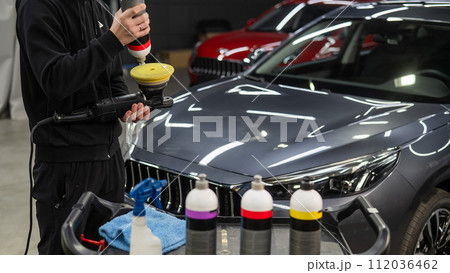 The master applies a special composition to the device for polishing the surface of the car body. The master applies a special composition to the device for polishing the surface of the car body. 112036462