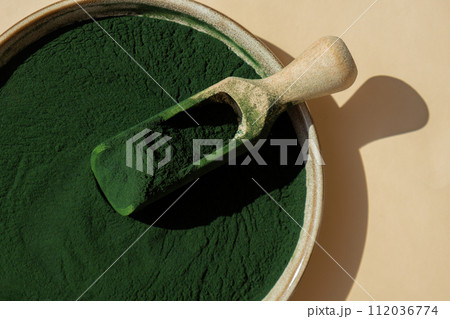 Organic blue-green algae spirulina powder food in plate with wooden spoon. Copy space for your text Health benefits of spirulina chlorella. Vitamins and minerals to diet. Detox dietary supplement 112036774