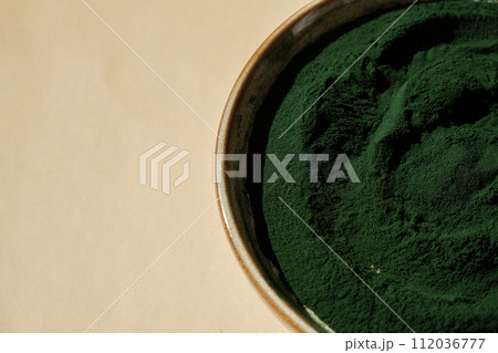 Natural organic green spirulina algae powder in bowl on neutral background. Chlorella seaweed vegan superfood supplement source and detox. Copy space Healthy nutritional antioxidant 112036777