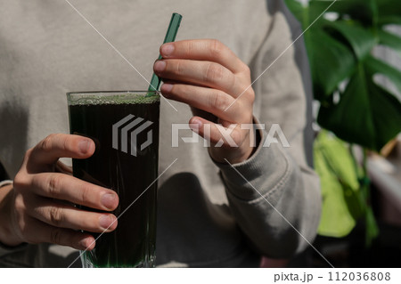 Female hands holding Organic blue-green algae spirulina detox drink in glass powder food. Health protein cocktail smoothie of chlorella. Vitamins and minerals to diet. Prebiotic and antioxidant rich 112036808