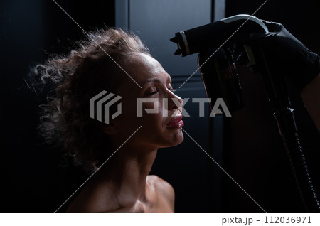 A master applies tinting paint to the face of a Caucasian woman. Instant tanning procedure A master applies tinting paint to the face of a Caucasian woman. Instant tanning procedure 112036971