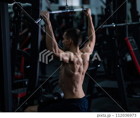 A man does a chest pulldown in the gym. 112036973