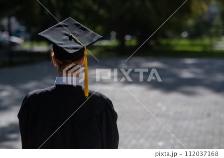 A woman throws her graduation cap against the blue sky. A woman throws her graduation cap against the blue sky. 112037168