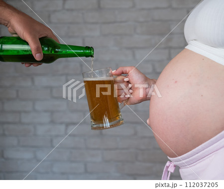 Man pouring beer for pregnant woman. Man pouring beer for pregnant woman. 112037205