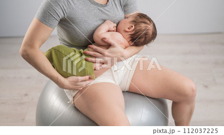 A faceless woman rocks her newborn son on a fitball. A faceless woman rocks her newborn son on a fitball. 112037225