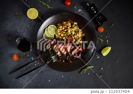 Sliced Organic grilled Tuna fillet covered with sesame seeds and salsa on black ceramic plate Sliced Organic grilled Tuna fillet covered with sesame seeds and salsa on black ceramic plate 112037404