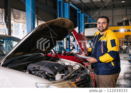 Portrait garage auto mechanic worker working checking car engine in car service center, Indian professional male working Portrait garage auto mechanic worker working checking car engine in car service center, Indian professional male working 112039335