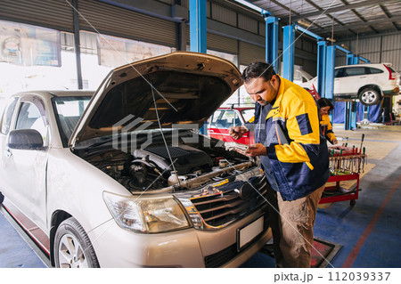 Garage auto mechanic worker working check engine oil level stick in car service center, Indian professional male working Garage auto mechanic worker working check engine oil level stick in car service center, Indian professional male working 112039337