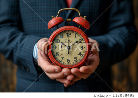 Businessman pulls the alarm clock arrow back, the alarm clock is the same size as the businessman. 112039498