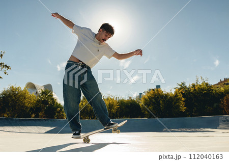 A young man doing tricks on his skateboard at the skate park. Active sport concept 112040163