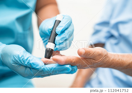 Doctor check diabetes from finger blood sugar level with finger lancet. 112041752