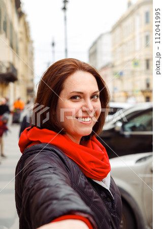 looking at camera smiling young Caucasian white female woman holds out hand to her partner on street of european city. follow me, date, love, valentine's day concept. lifestyle portrait looking at camera smiling young Caucasian white female woman holds out hand to her partner on street of european city. follow me, date, love, valentine's day concept. lifestyle portrait 112041995