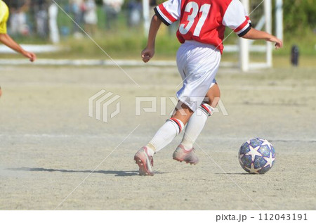 少年サッカーの試合（ドリブルする選手） 112043191