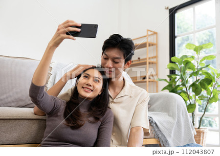 Happy couple asian young women happy smile and taking selfie on couch in living room at home 112043807