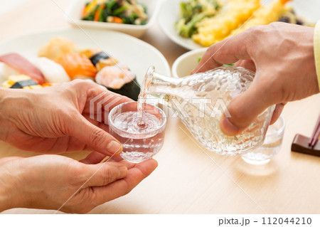 冷酒と和食で晩酌をする夫婦 112044210