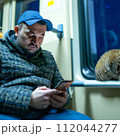 AI-generated content. A man with a cat and smartphone in public transport. High quality photo 112044277