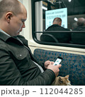 AI-generated content. A man with a cat and smartphone in public transport. High quality photo 112044285