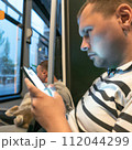 AI-generated content. A man with a cat and smartphone in public transport. High quality photo 112044299