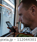 AI-generated content. A man with a cat and smartphone in public transport. High quality photo 112044301