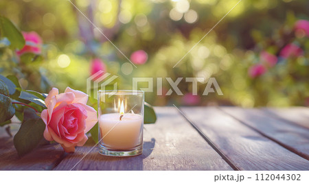 AI-generated content. A candle and rose on a wooden table, with a lush garden backdrop. 112044302