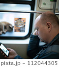 AI-generated content. A man with a cat and smartphone in public transport. High quality photo 112044305