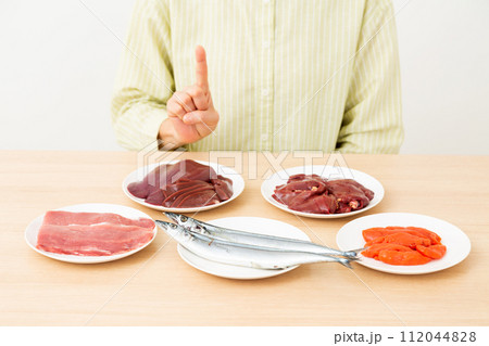 ビタミンB群を多く含む食品と人差し指を立てるミドル女性 112044828